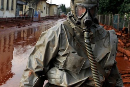 A Hungarian soldier wearing chemical protection gear walks through a street flooded by toxic sludge in the town of Devecser, Hungary on Tuesday, Oct. 5, 2010. (AP Photo/Bela Szandelszky)