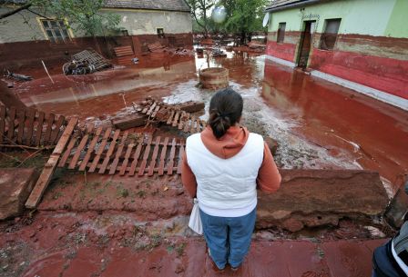 A woman contemplates the damage in Devecser, Hungary on October 5, 2010 after the village was flooded by toxic red sludge. (ATTILA KISBENEDEK/AFP/Getty Images)