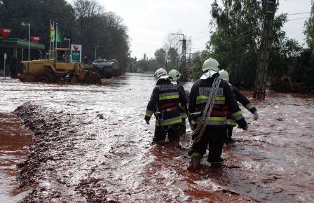 Local residents are rescued by excavators next to a gas station while firefighters in the foreground wade through the mud in Devecser, Hungary on Monday, Oct. 4, 2010. (AP Photo/MTI, Lajos Nagy)